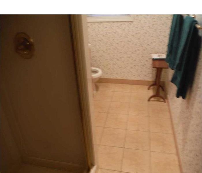 Water damaged bathroom in need of floor removal and dry down services.