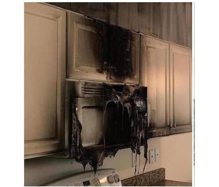 completely melted microwave and smoke damage in white kitchen