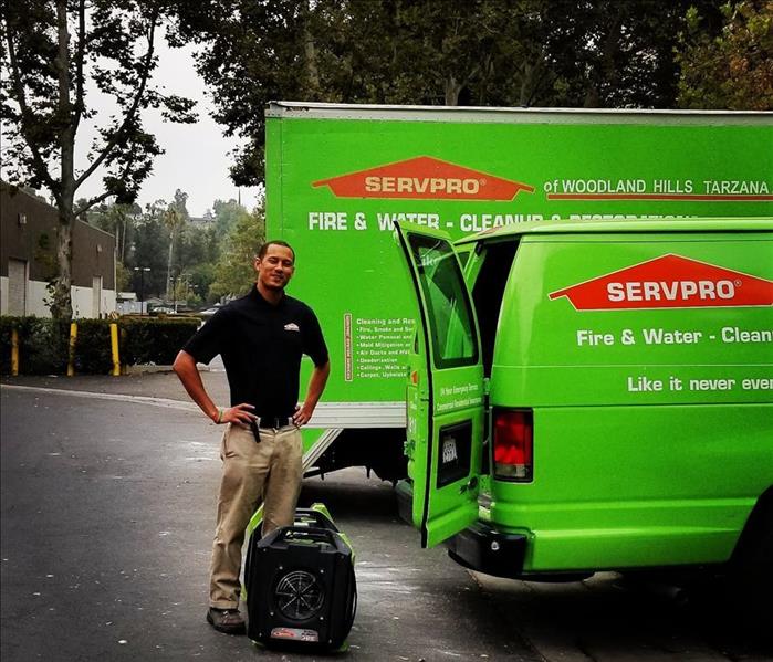Employee standing by 2 SERVPRO vehicles.